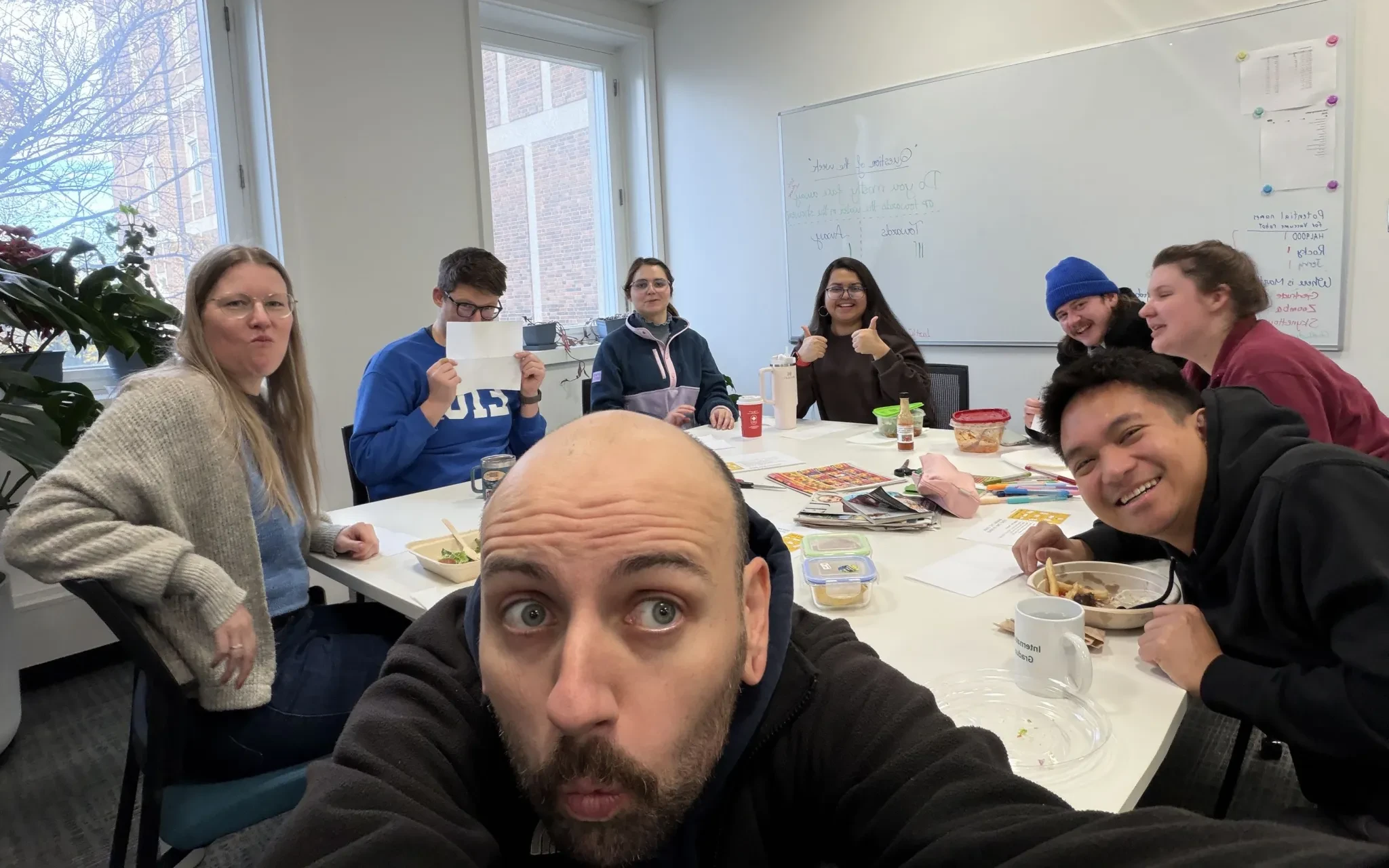 A group selfie of COSSEE members sharing lunch around a meeting room table