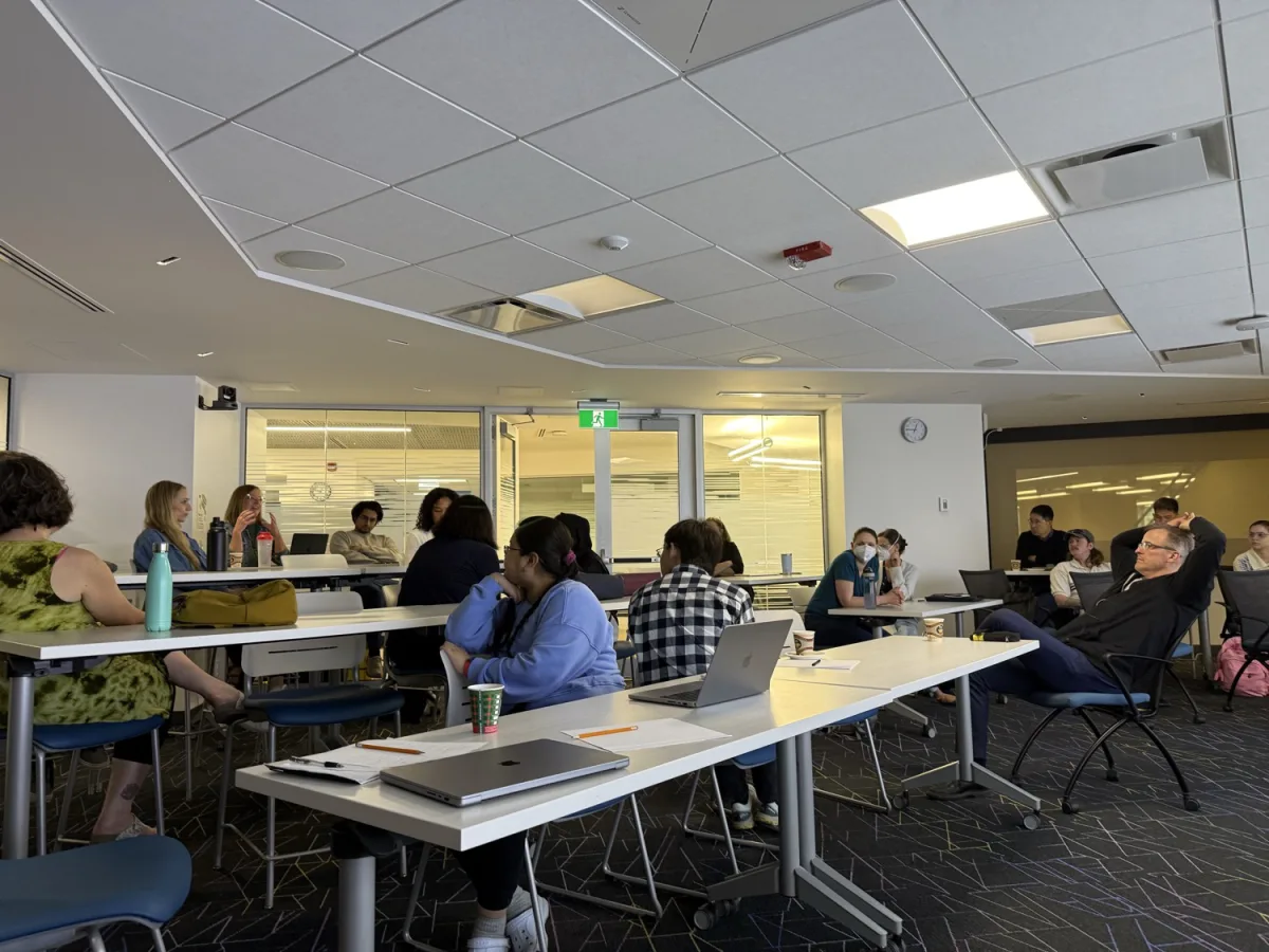 Workshop participants seated around tables in small groups during the breakout discussion tracks.