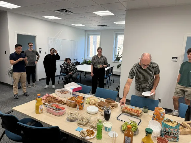 A potluck table spread with food as COSSEE members gather around it.
